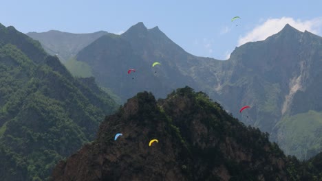 los pilotos de parapente vuelan parapentes entre nubes y montañas verdes.