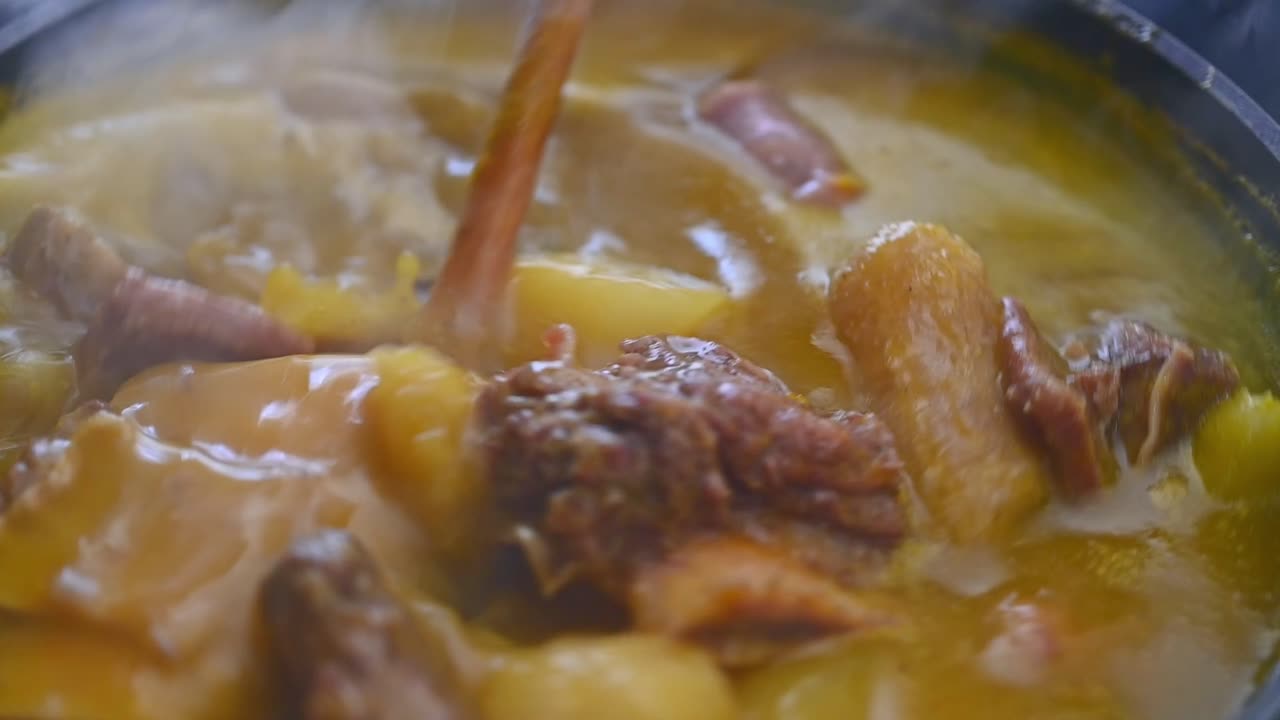 vista de cerca de la cuchara de madera que muestra la carne humeante de la comida criolla dominicana tradicional llamada sancocho