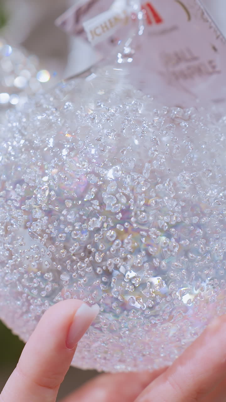 Close up hand view of person touching sparkling decorative material in home decor shop, beautiful shiny ornaments and decor items displayed for holiday season shopping