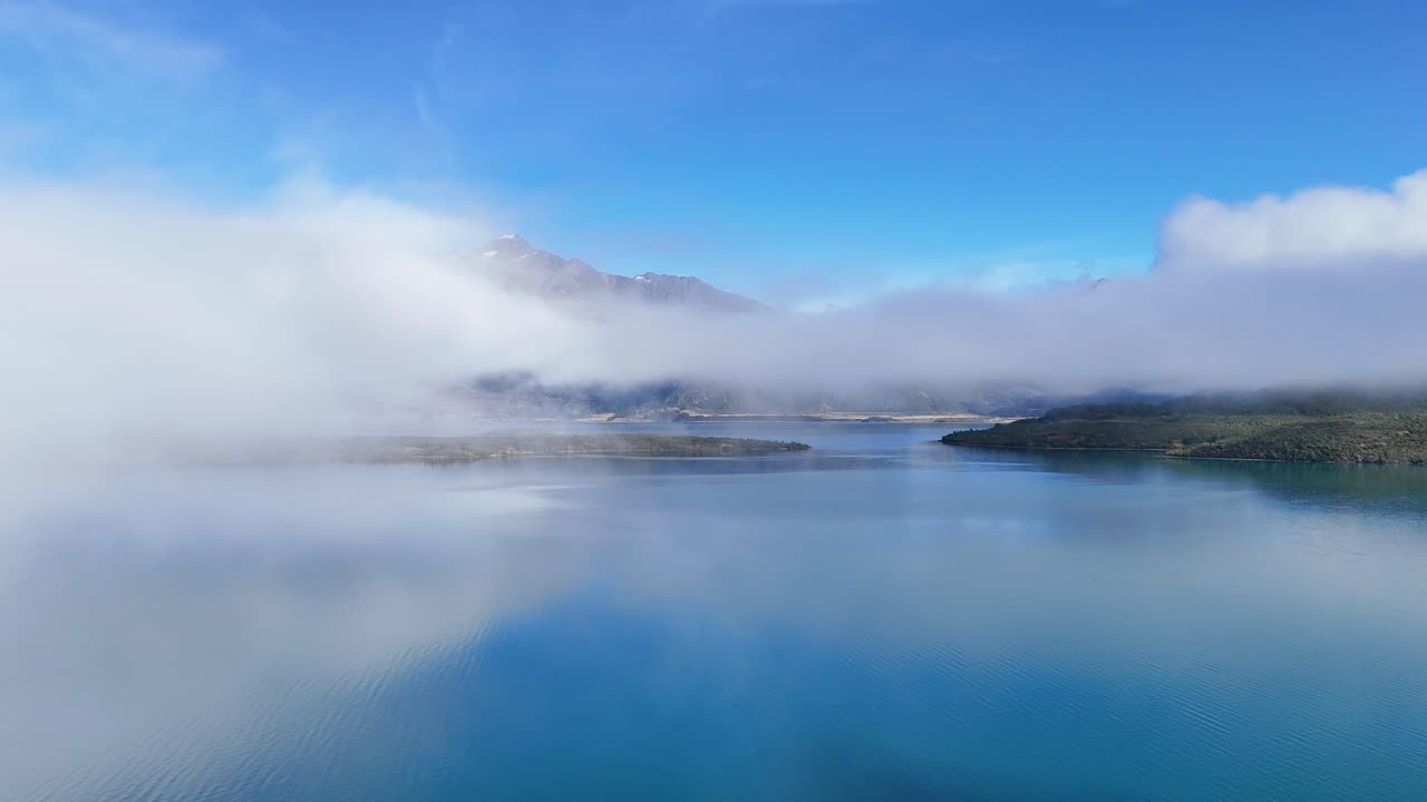 Aerial footage reveals Lake Wakatipu's serene beauty, with misty clouds and mountains under clear blue skies