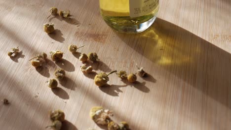 chilled chamomile liquor bottle with dried flowers scattered on a wooden surface