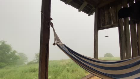 Hängende-Hängematte---Holzschaukel-Auf-Einer-Entspannenden-Sommerhaus-Terrasse,-An-Einem-Nebligen-Tag-In-Der-Natur