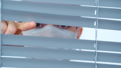 woman wearing mask looking through blinds