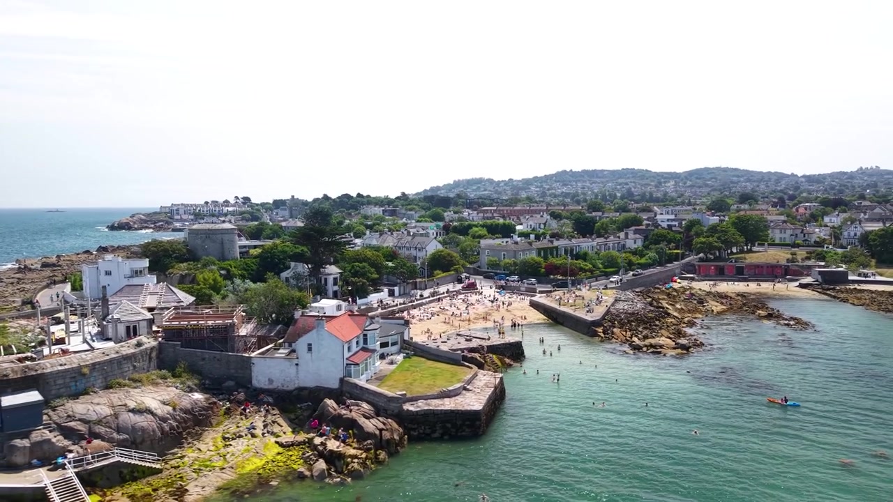 Veduta aerea estiva dorata di Forty Foot e della spiaggia di Sandycove con mare cristallino, Irlanda