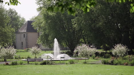 Serena-Escena-De-Parque-Con-Una-Fuente-Central,-Bancos-Y-Exuberante-Vegetación.