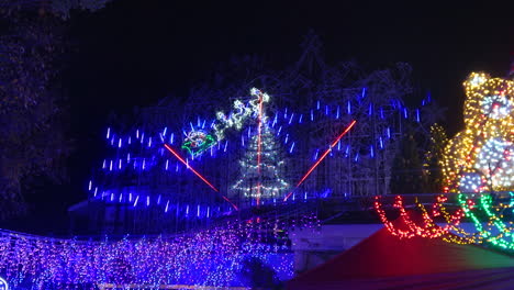 extravagant christmas light display with motorized train falling snow at night -- 4k