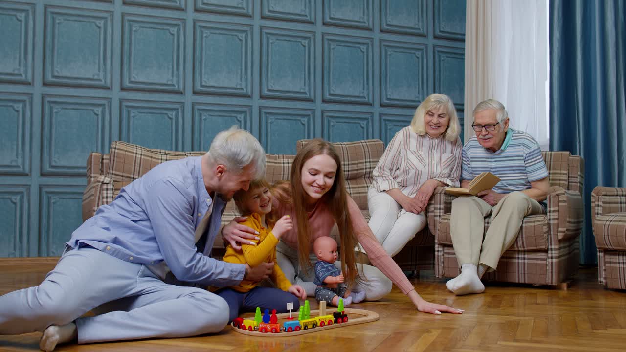 Happy family leisure at home child daughter playing with mother and father railway toy game on floor