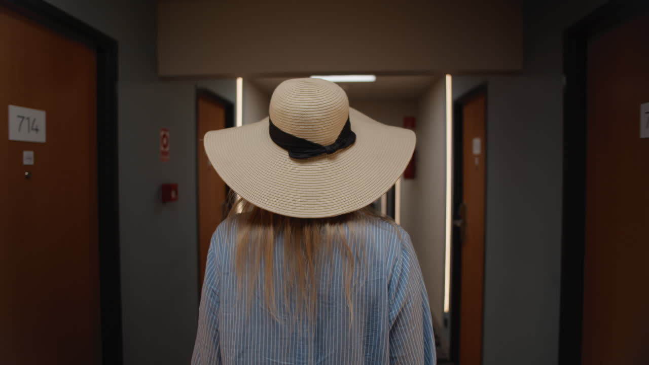 Woman in hat walking down hotel corridor