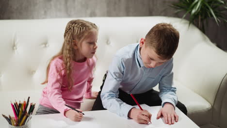 little blonde girl looks at friend to copy homework at home