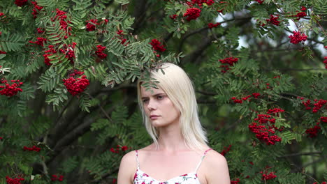 A-young-woman-stands-against-the-backdrop-of-trees-in-a-park,-forest-or-garden