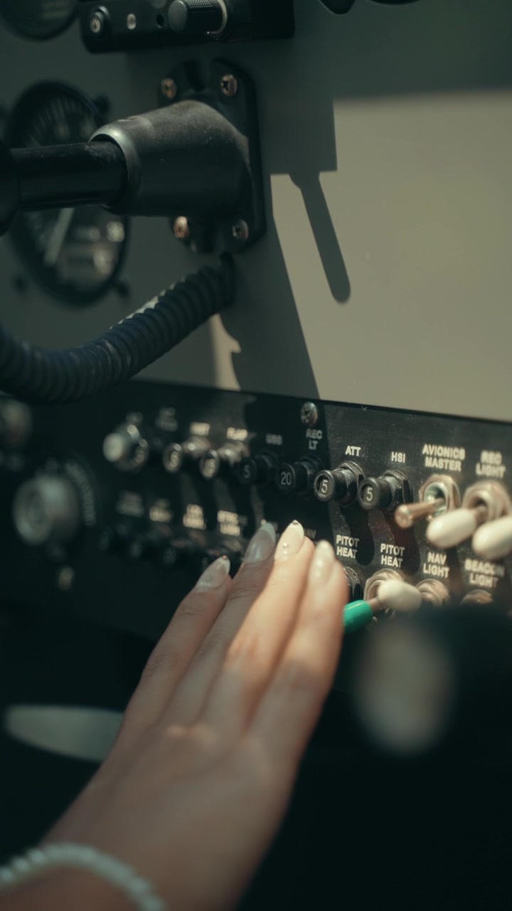 Student pilot hand checks circuit breakers avionics switches and instrument panel inside small aircraft cockpit before flight
