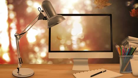 desktop computer and office equipment on a table against autumn maples leaves falling in background