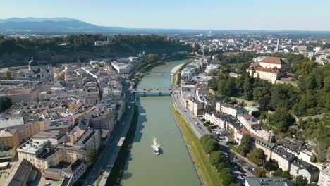 drone flies backward above salzach river in salzburg, austria