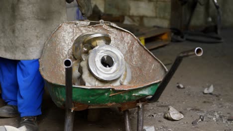 male worker standing with metal casting in workshop 4k