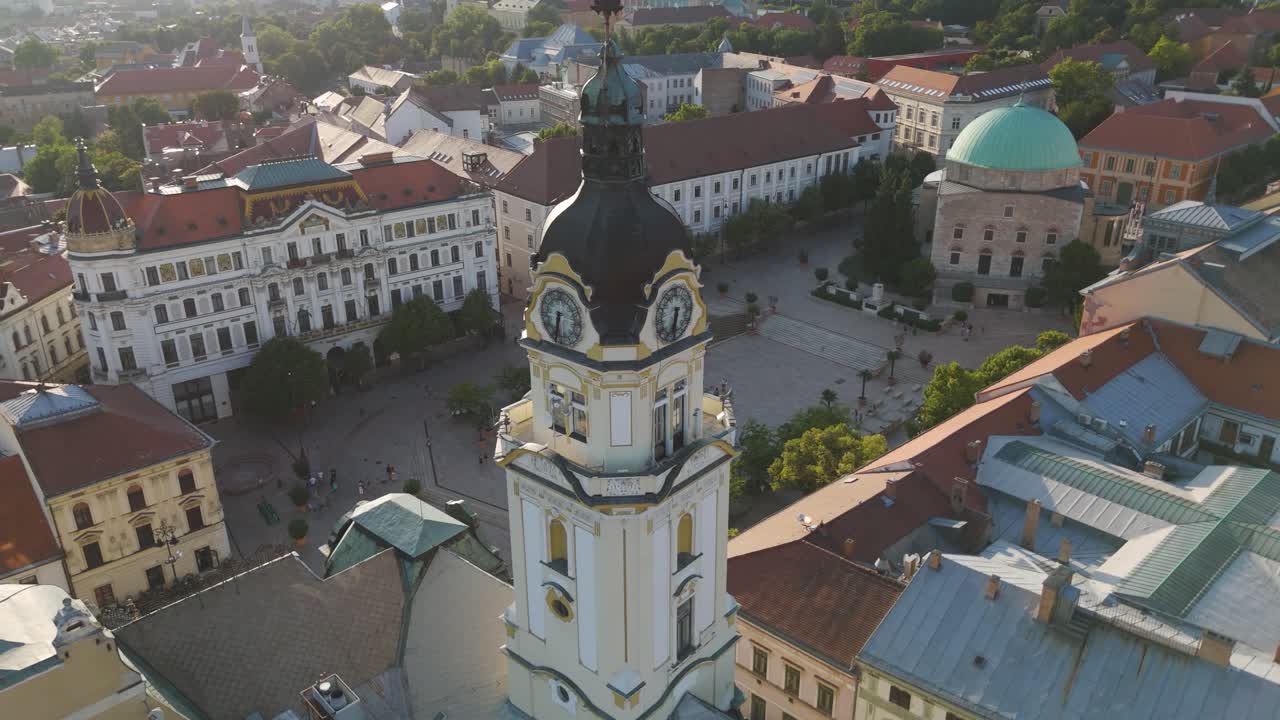 Orbiting Pécs Town Hall clock tower in Széchenyi Square, showcasing the historic square and surrounding cityscape