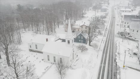 blizzard snowfall over church small town aerial