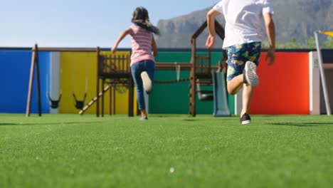 Vista-Trasera-De-Escolares-De-Raza-Mixta-Jugando-En-El-Patio-De-La-Escuela-4k