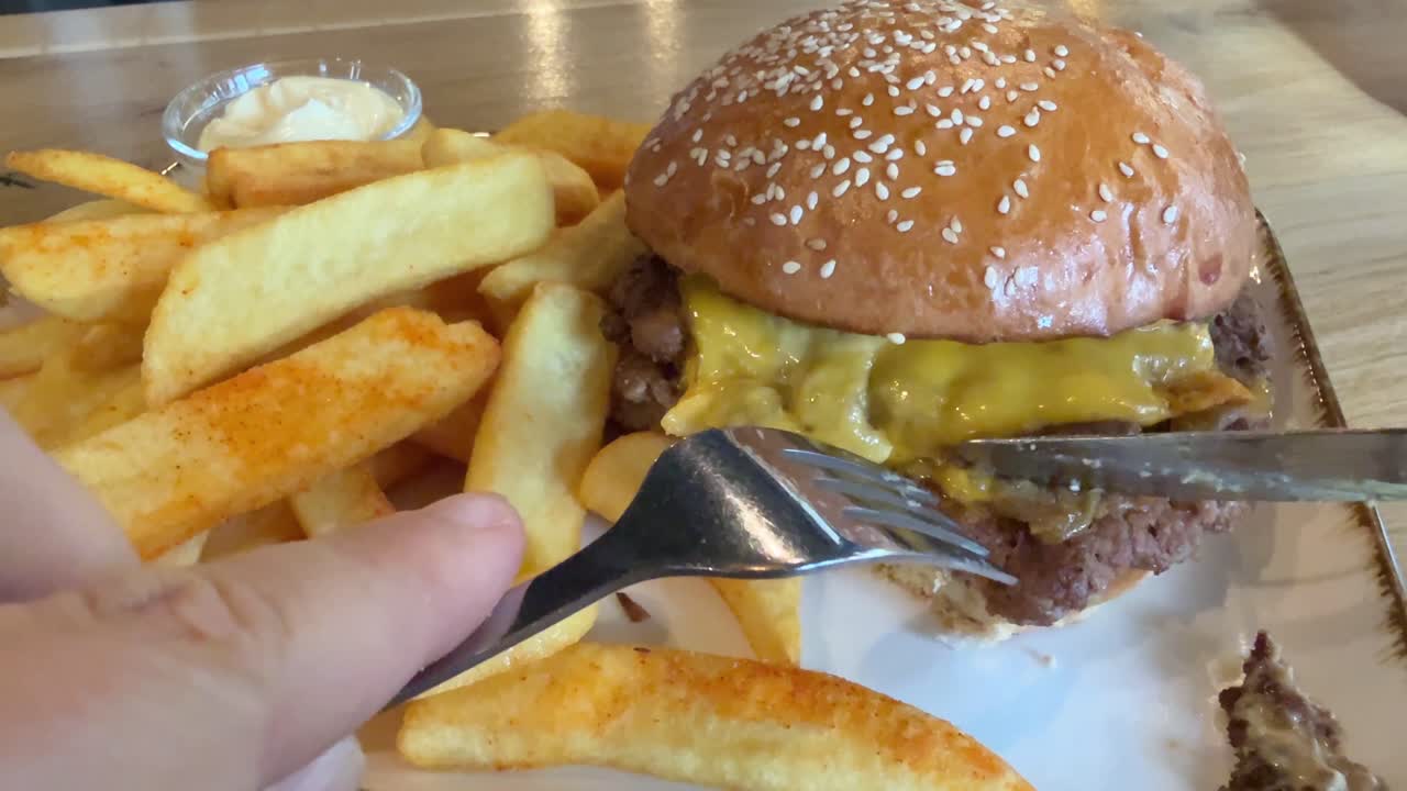 Eating a cheeseburger with French fries