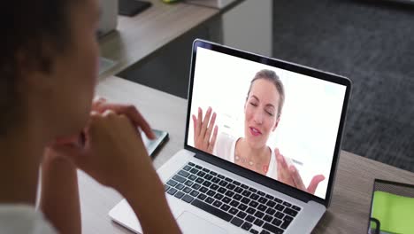 sección media de una mujer afroamericana haciendo una videollamada con una colega en una computadora portátil en la oficina
