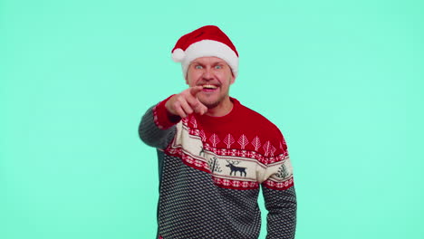 Man-in-red-Christmas-sweater-smiling-excitedly,-pointing-to-camera,-beauty-choosing-lucky-winner