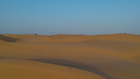 Drohne-Fliegt-Durch-Die-Wüste,-Während-Sich-Sanddünen-Mit-Blauem-Himmel-Im-Hintergrund-In-Wahiba-Sands-In-Oman-Auf-Den-Betrachter-Zubewegen