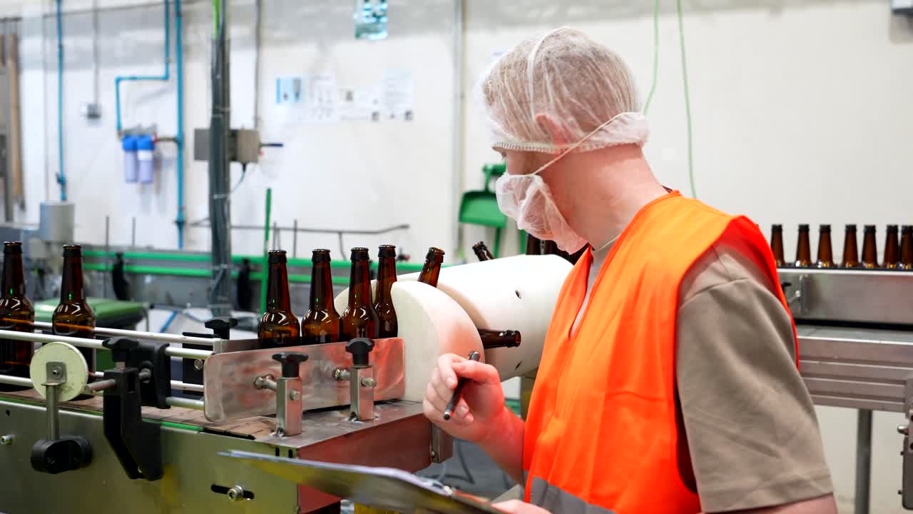 Worker Inspecting Beer Bottles on Production Line