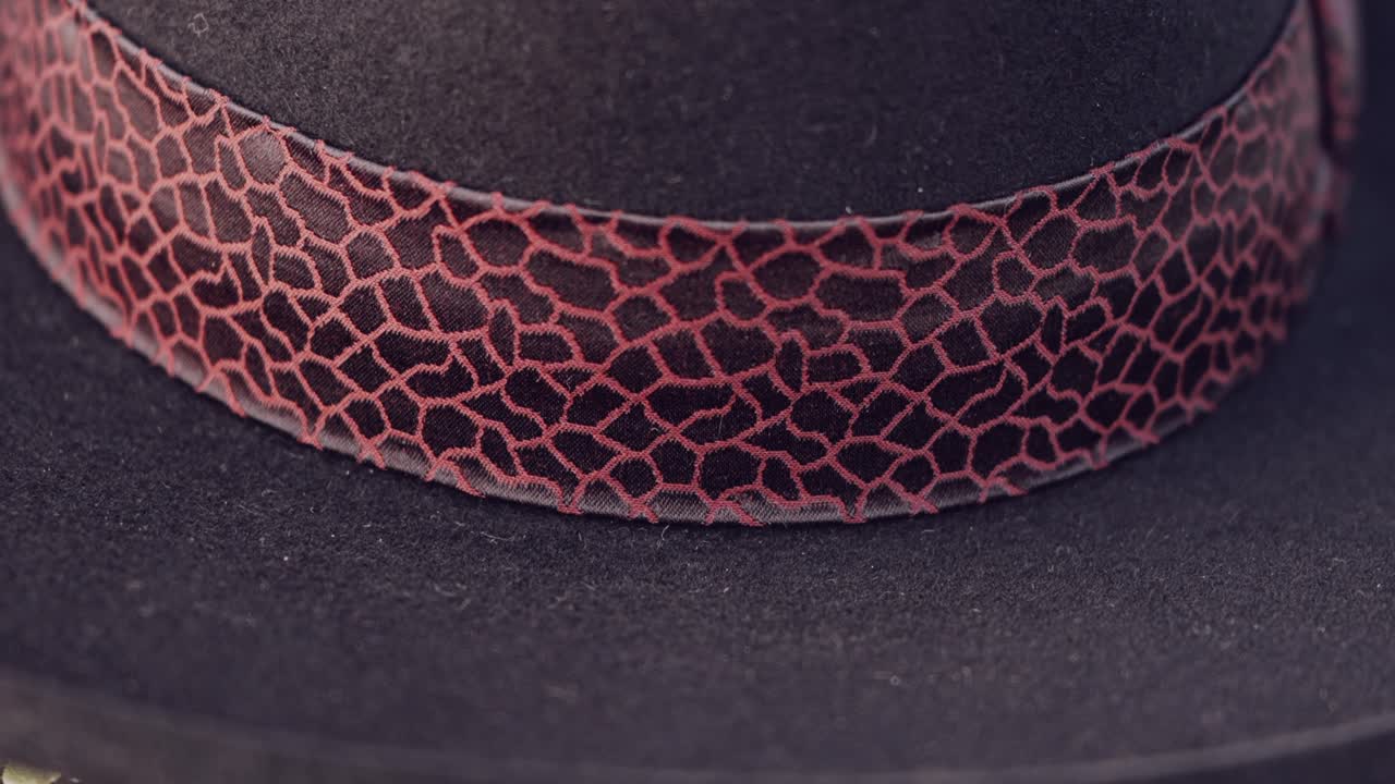 Detailed close up of a dark hat with an intricate patterned band design