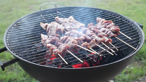 placing pork spare ribs on a charcoal bbq next to chicken skewers