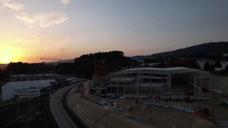 Fly-Above-Industrial-Building-Construction-with-Crane-at-sunset