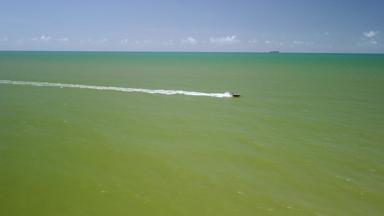 케언즈의 트리니티 해변에서 바다를 가로질러 과속하는 보트의 조감도