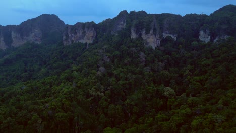 limestone cliffs and lush tropical jungle of railay beach, krabi, thailand, at dusk, creating a dramatic and serene landscape. amazing aerial view flight overflight flyover drone