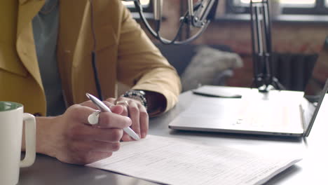 Manos-De-Hombre-Tomando-Notas-En-Una-Mesa-Con-Laptop-Y-Micrófono-1