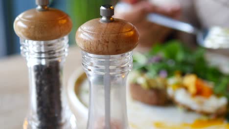 mesa con molinos de pimienta y sal y plato de desayuno