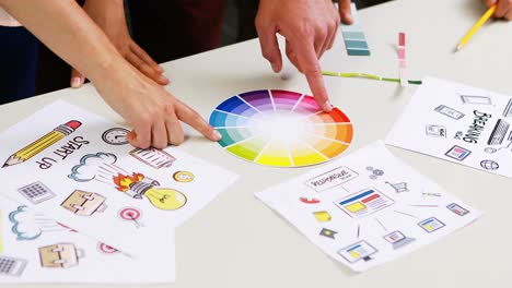 graphic designers discussing over color swatch at desk