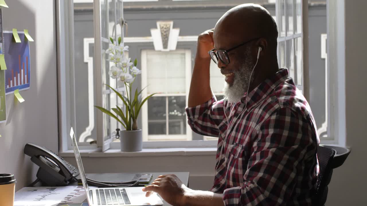 Senior male executive using laptop at desk 4k