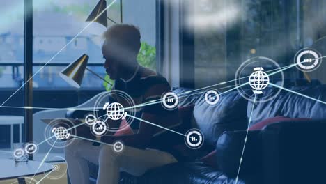 animation of network of connections with icons over african american businessman using tablet