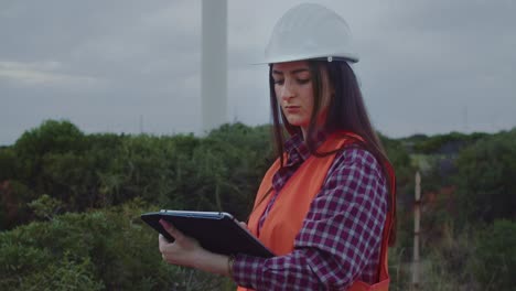 Mittlere-Nahaufnahme-Einer-Windmühlentechnikerin-Verwendet-Tablet,-Um-Windturbinen-Zu-Inspizieren