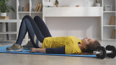 Una-Joven-Atlética-Está-Haciendo-Ejercicios-Deportivos-En-Casa-Levantando-Caderas-Para-Entrenar-Músculos,-Actividad-Física-Y-Bienestar,-Estilo-De-Vida-Saludable.