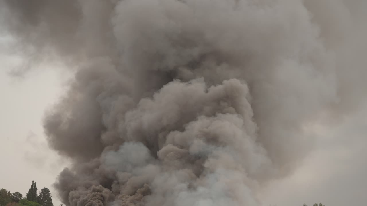 Black smoke clouds and flames rise into the sky.