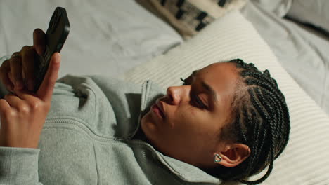 young woman using phone in bed at night