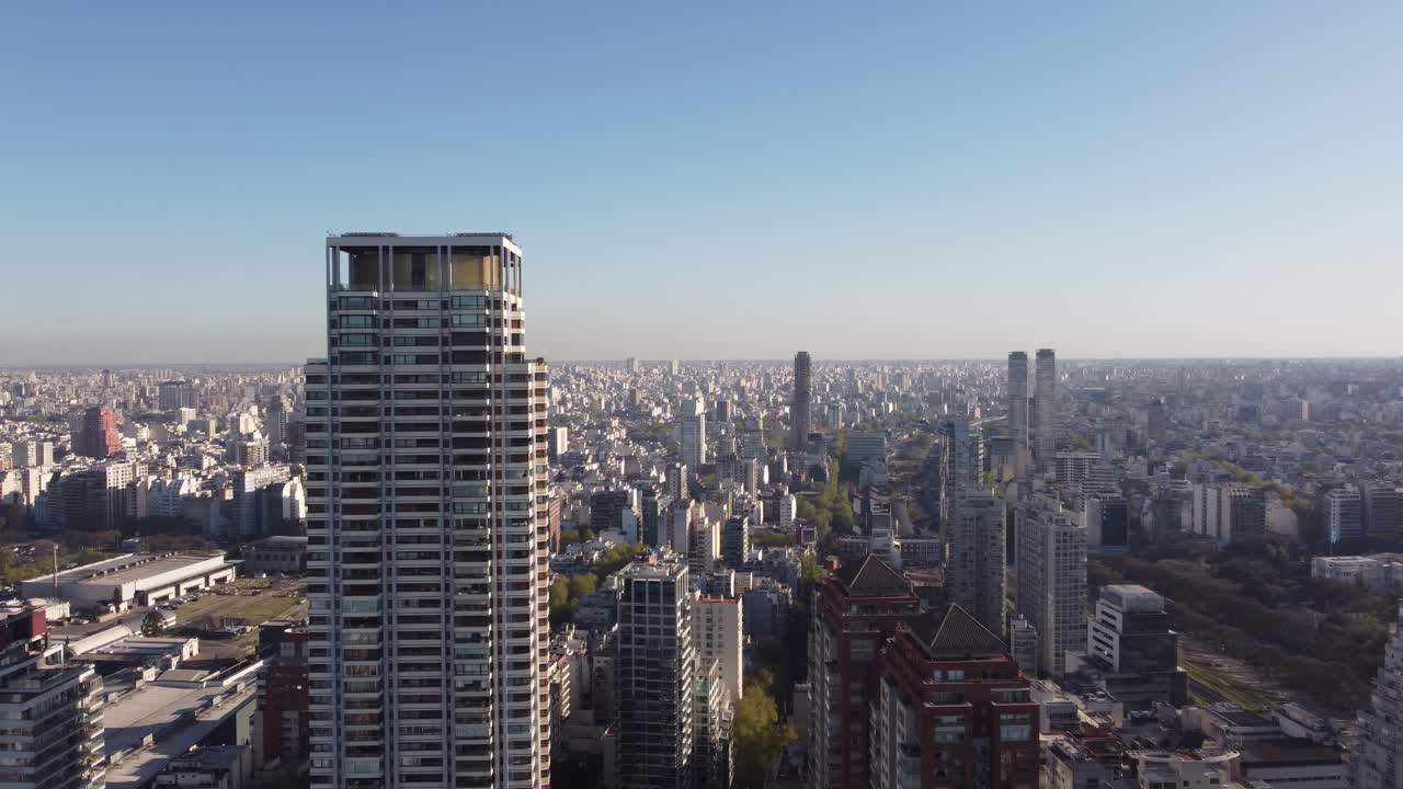 la parte superior de una gran torre es el rascacielos le parc con la ciudad de buenos aires al fondo al atardecer
