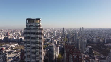 the top of a large tower is the le parc skyscraper with the city of buenos aires in the background at sunset