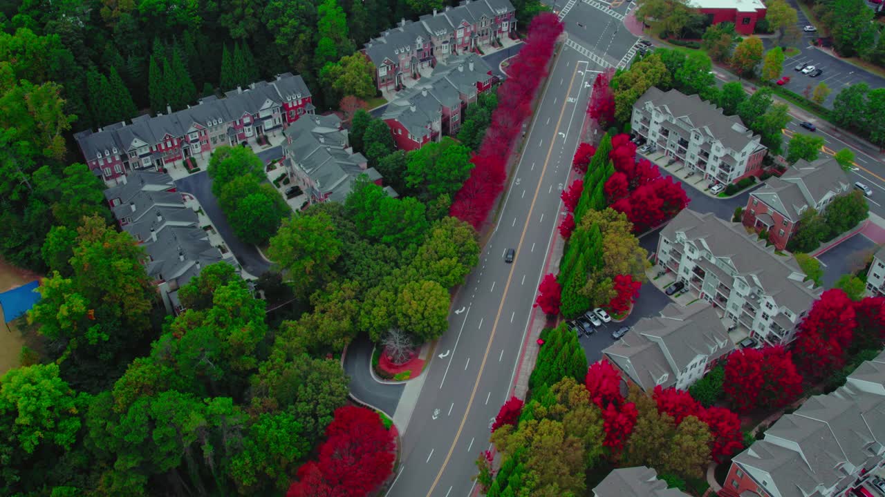 Bird's-eye view of a car on a winding road amidst vibrant autumn trees in Atlanta suburbs