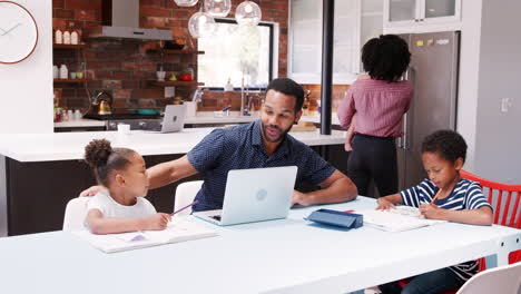 Father-Helps-Children-With-Homework-Whilst-Mother-Holds-Baby