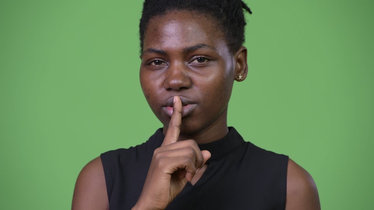 Young beautiful African businesswoman with finger on lips