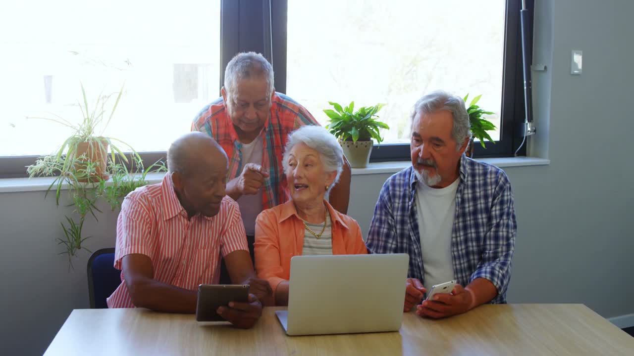 Happy senior friends interacting with each other while using laptop 4k