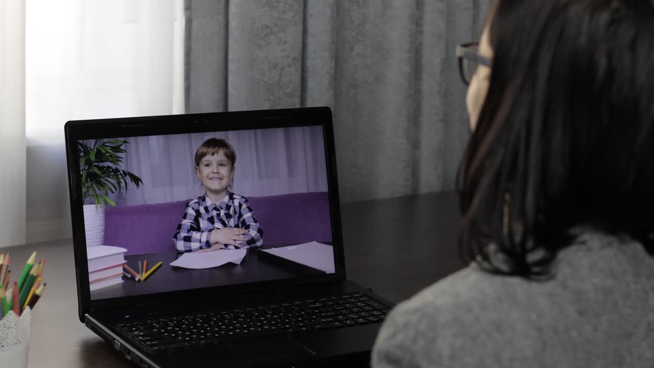 Woman teacher making video call on laptop with little pupil. Distance education