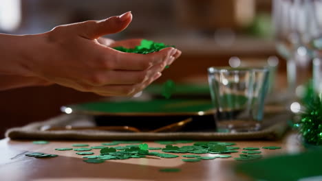 hands sprinkling green shamrock confetti on a table