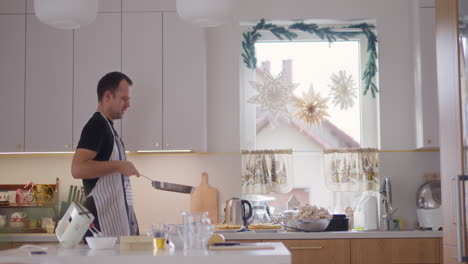 man flips pancakes on a frying pan