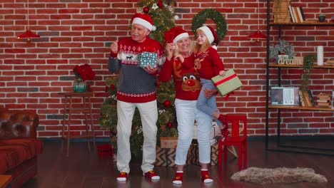 Glückliches-Altes-Großelternpaar-Mit-Enkelin,-Das-Tanzen-In-Der-Nähe-Des-Weihnachtsbaums-Feiert